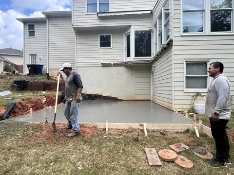 Crew pouring a concrete patio behind a house