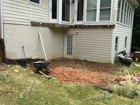 Ground cleared and shaped for a new patio behind a house