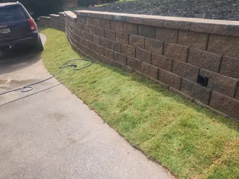 Block retaining wall along a driveway with new sod