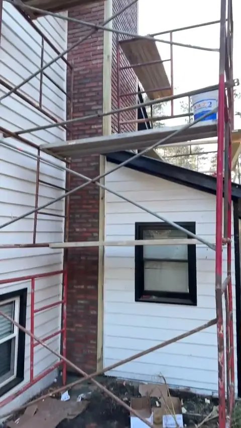 Exterior siding and chimney work from scaffolding